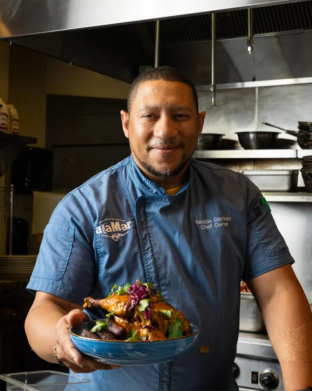 Chef Nelson German with a finished dish at alaMar, Oakland