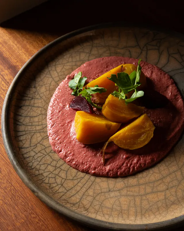 Golden beets over mole rosa on a rust plate at Amado, Burlingame