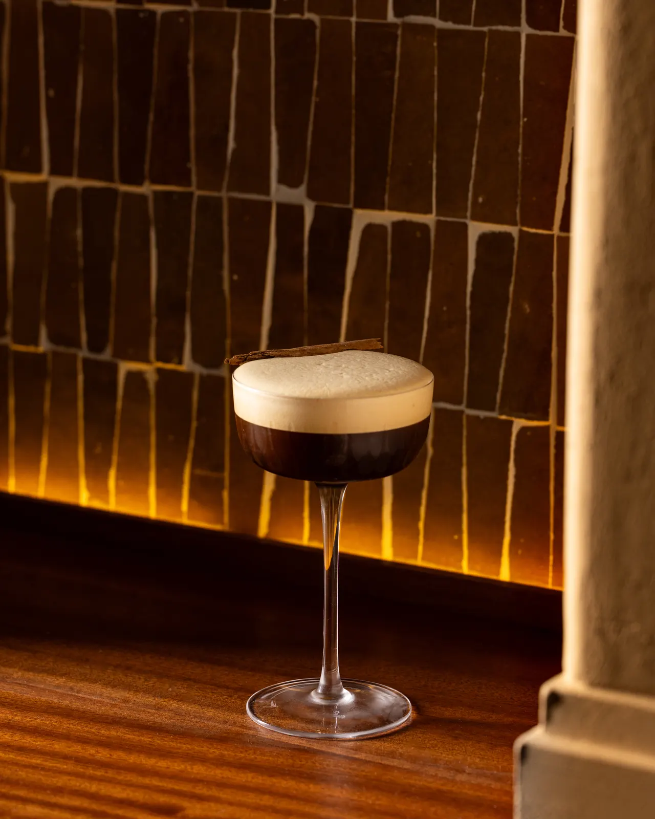An espresso martini on the bar against the amber tile wall at Amado, Burlingame