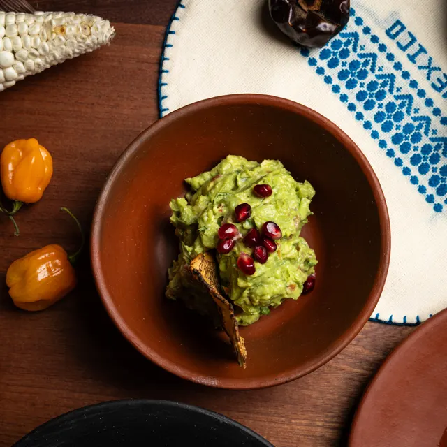 Guacamole with pomegranate in a molcajete beside habaneros at Amado, Burlingame