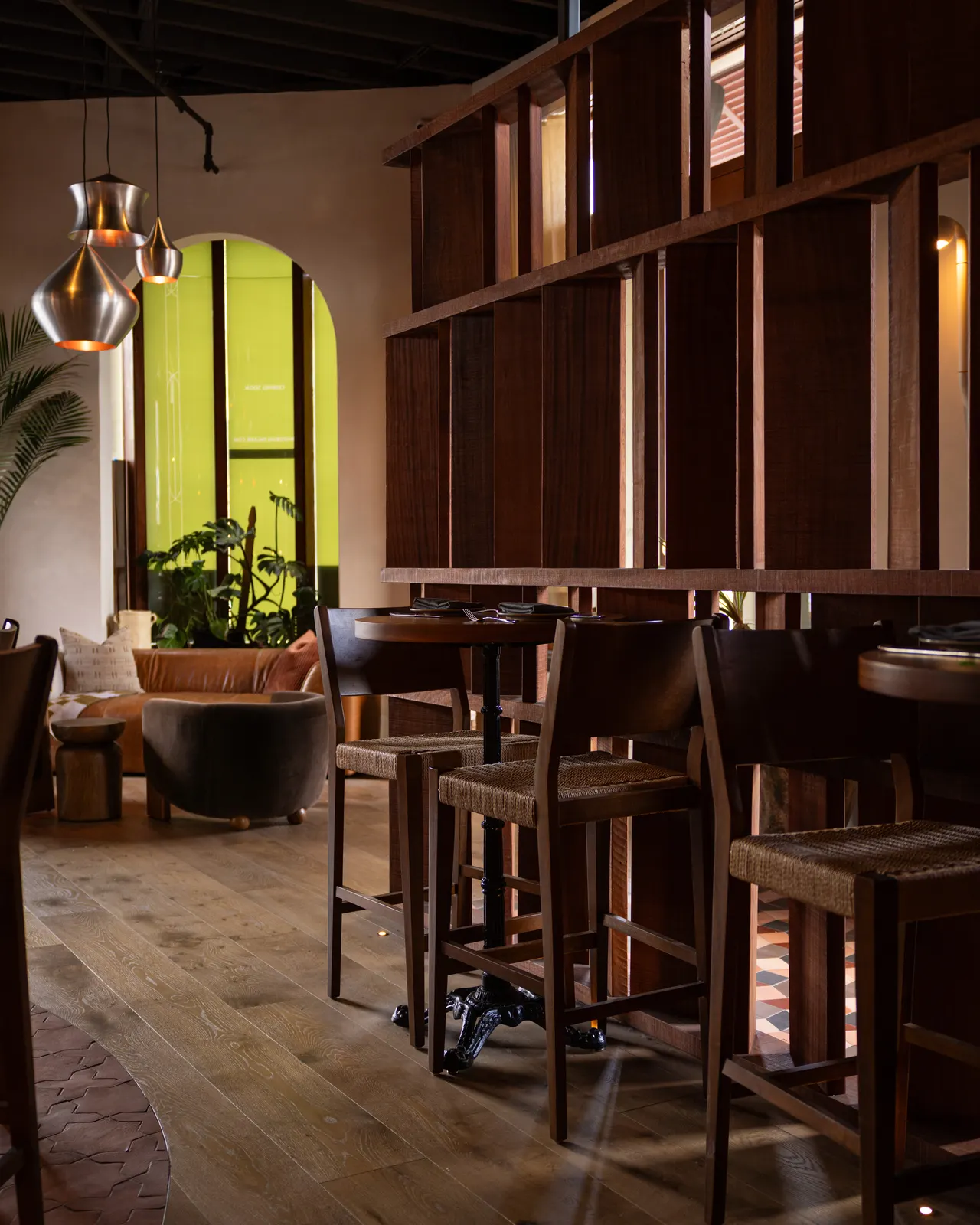 Bar seating against the slatted wood divider, lounge and green arch beyond, at Amado, Burlingame