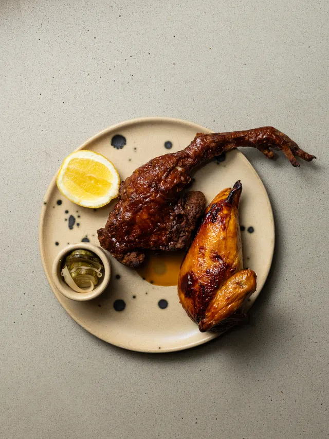 Crispy duck leg with charred lemon on a speckled plate at Arquet, San Francisco