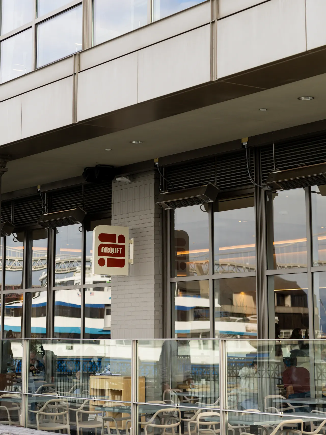 The glass-fronted corner of Arquet from the sidewalk, the dining room and its diners visible through the panes, San Francisco