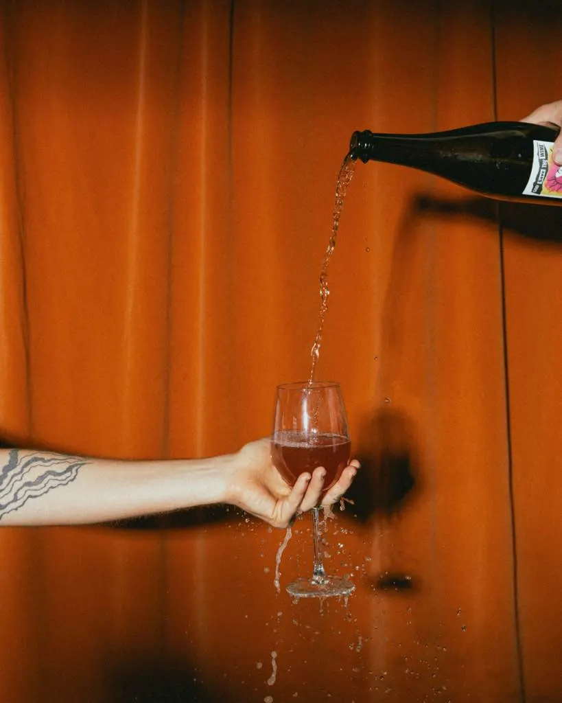 Wine poured from height against an orange curtain at The Black Cat, Livermore