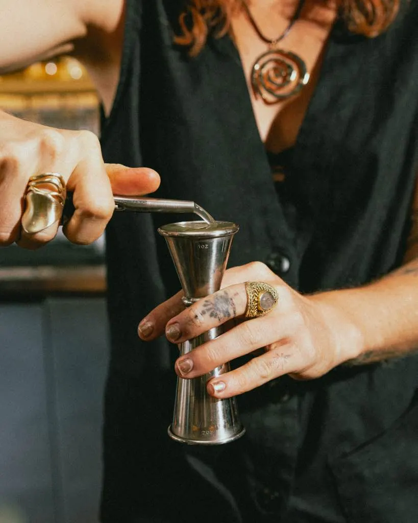 A bartender pours into a jigger in low light at The Black Cat, Livermore