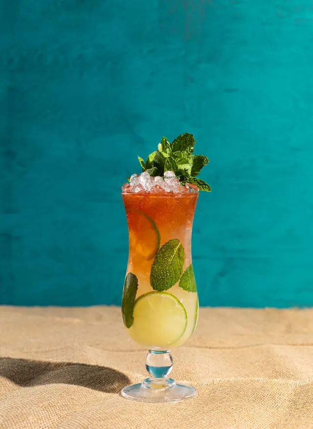A garnished hurricane against teal, from Caribbean Cocktails for Ten Speed Press