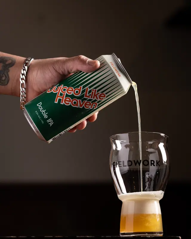 A Juiced Like Heaven double IPA poured into a branded glass for Fieldwork Brewing