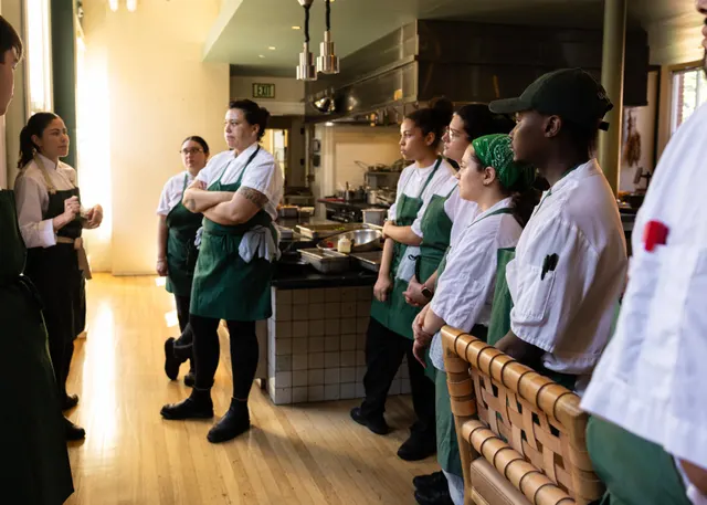 The kitchen line in green aprons, gathered in the hall before service