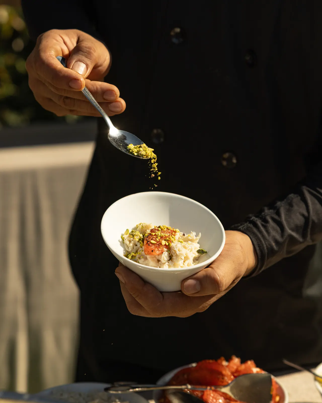 Crushed pistachio dusted over a crab bowl in golden light, for Handheld Catering, Santa Clara