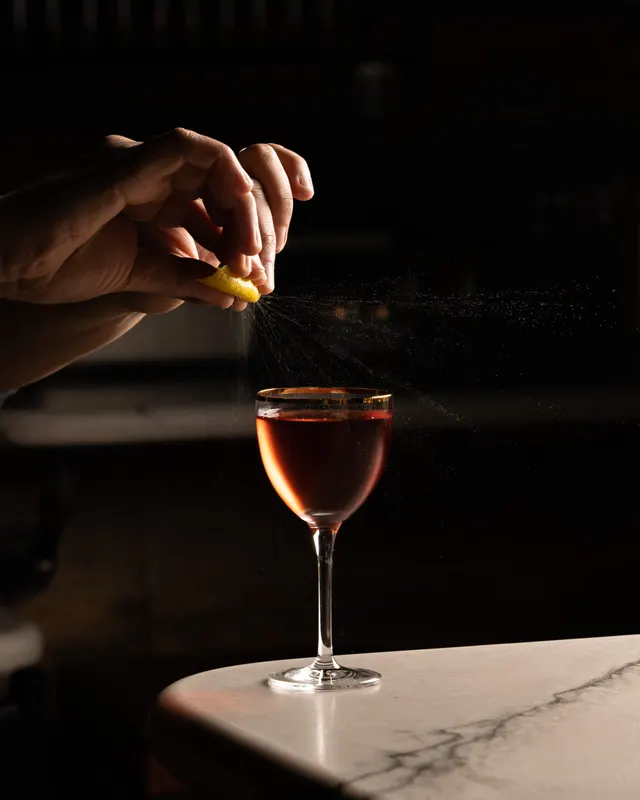 A lemon twist expressed over a cocktail in near-darkness at Sons of Liberty Alehouse, San Leandro