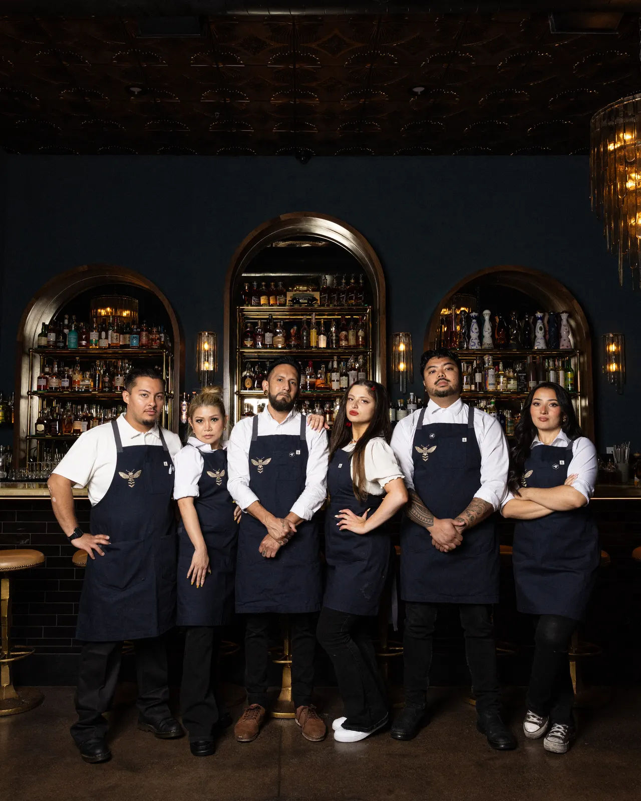 The Honeycomb Cocktail Lounge crew in matching aprons, lined up in front of the arched back bar, Livermore