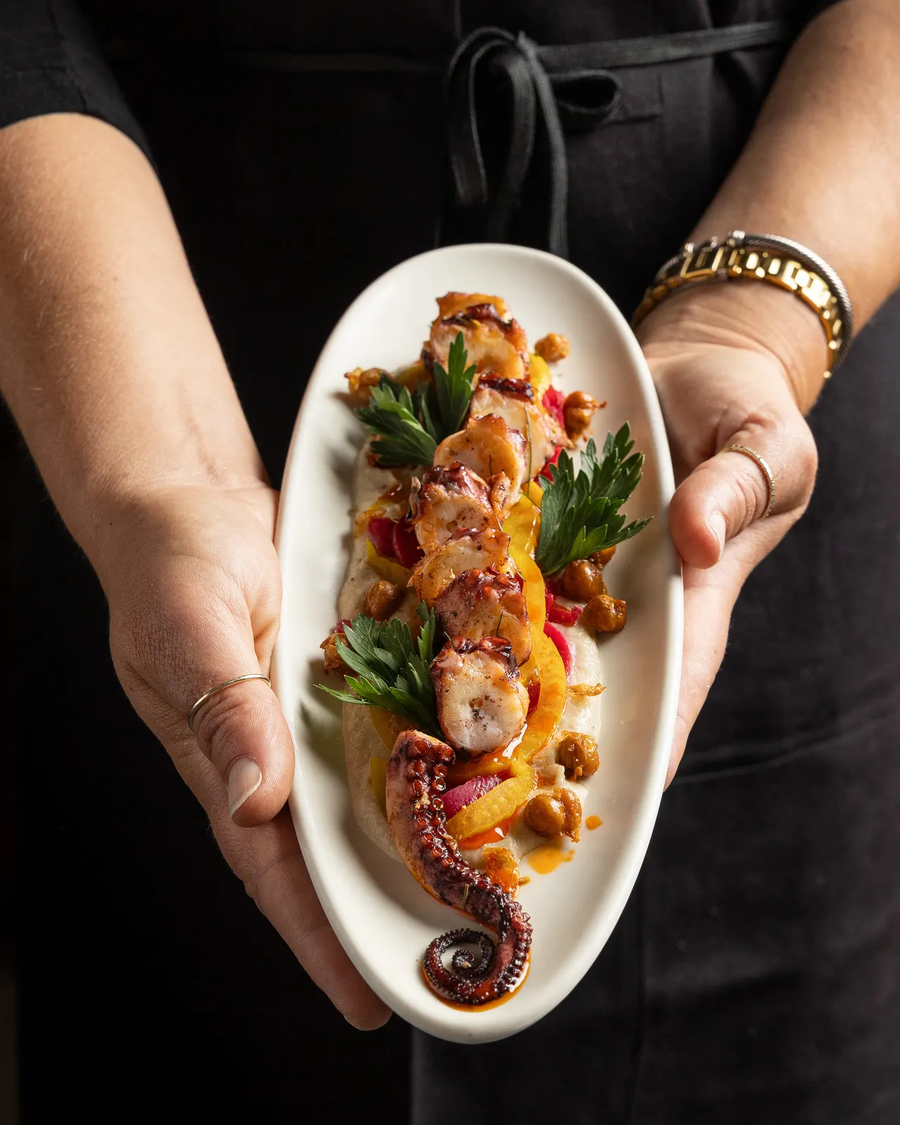 The octopus plate presented in two hands at La Marcha, Berkeley