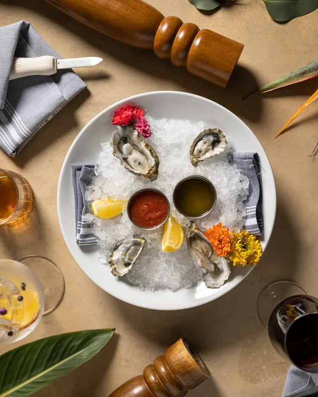 Oysters on crushed ice with mignonette and flowers beside a glass of red at Massimo Ristorante, Walnut Creek