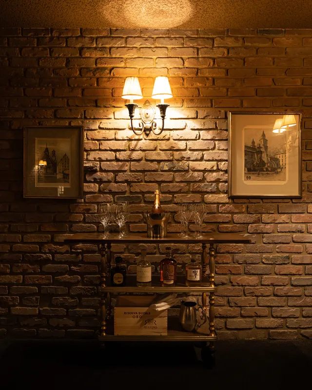 Brick, framed prints, and a lit sconce above the shelf at Massimo Ristorante, Walnut Creek