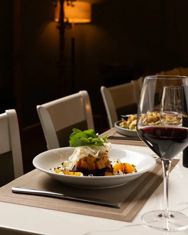 A plated tower and a glass of red in the dining room at Milan, San Jose