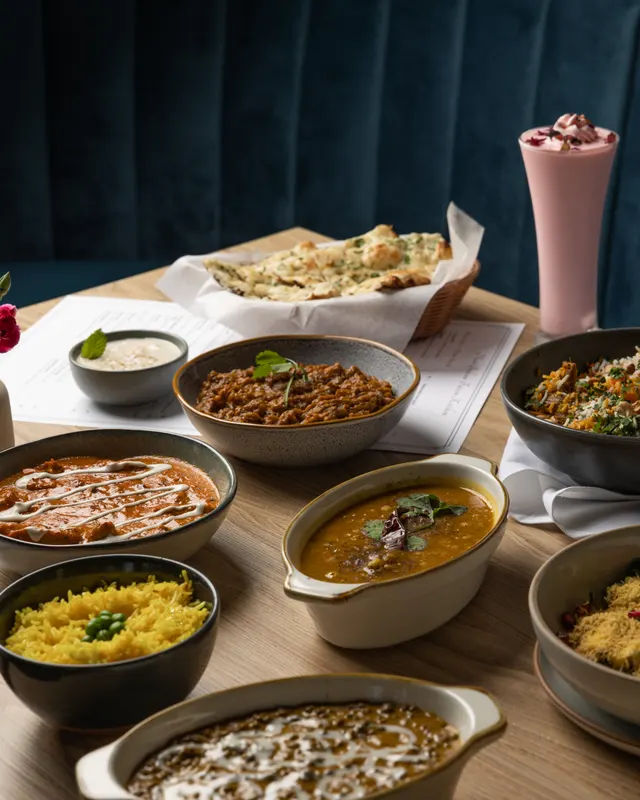 Curries and biryani against the teal banquette at Noor Fusion Kitchen, Berkeley