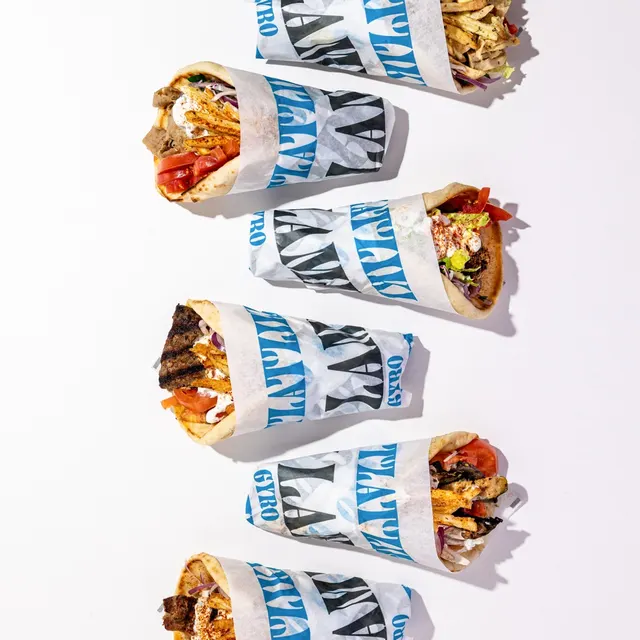 Wrapped gyros in branded paper, flat-laid on white for the Nick the Greek franchise