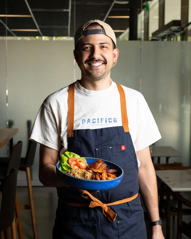 The chef holding a plated bowl in his Pacífico tee, San Francisco