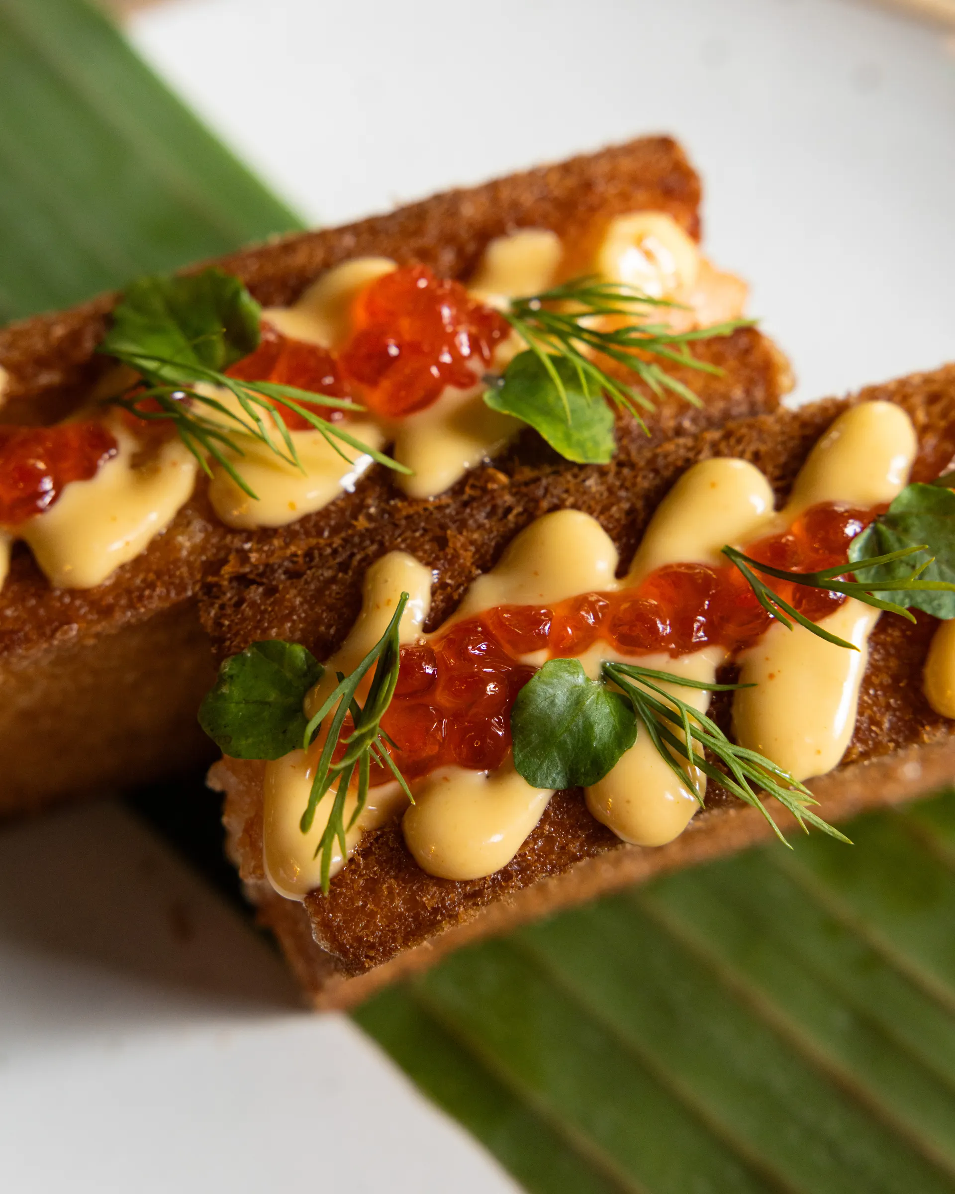 Fried toast fingers piped with aioli, salmon roe, dill and watercress on a banana leaf at Payakk, Oakland