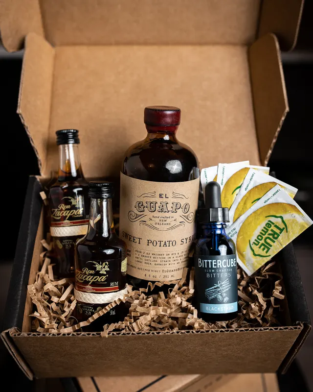 The SaloonBox cocktail kit packed for shipping: bitters, spirits, and citrus in the box