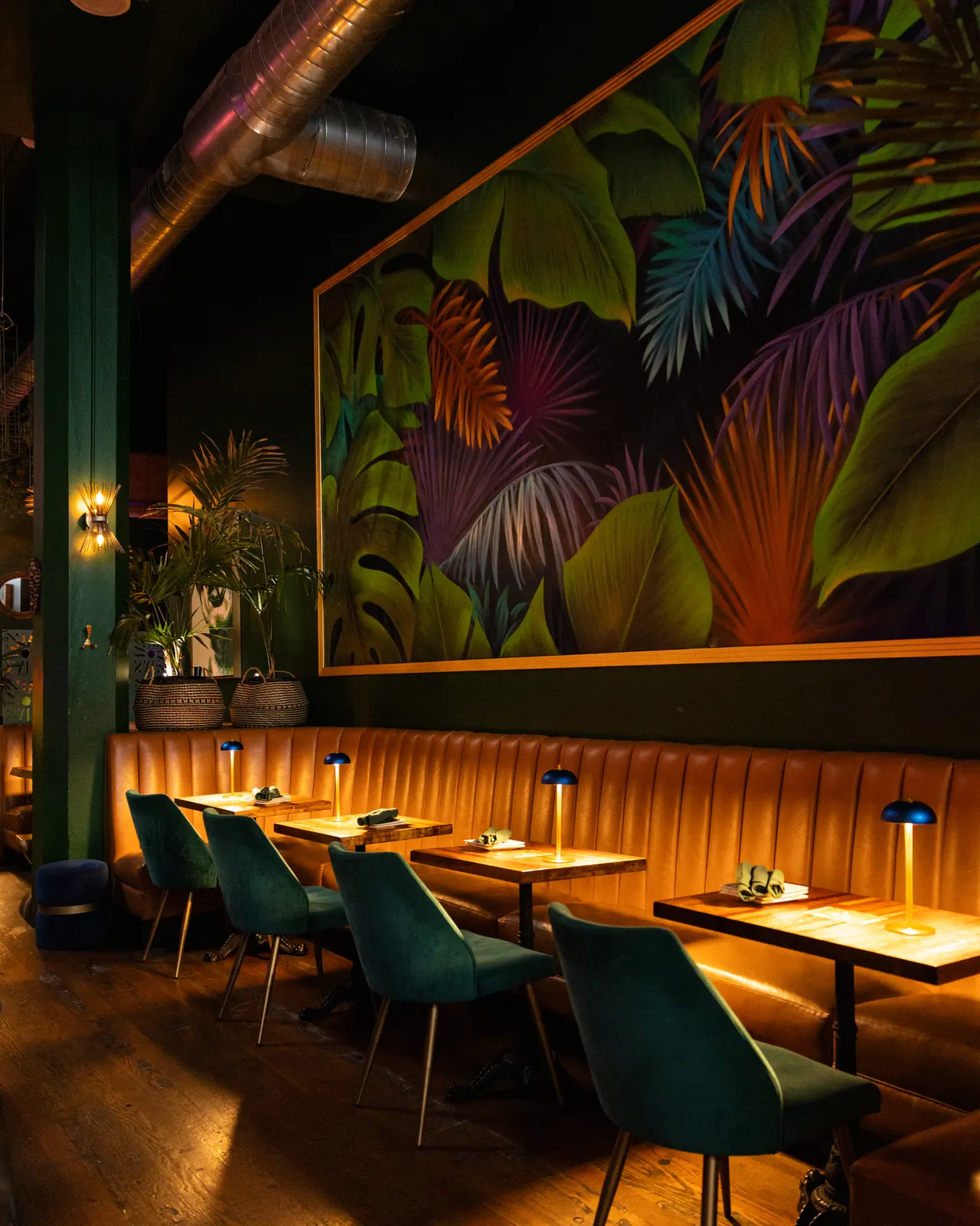 A tropical mural over the emerald lounge seating at Sobre Mesa, Oakland