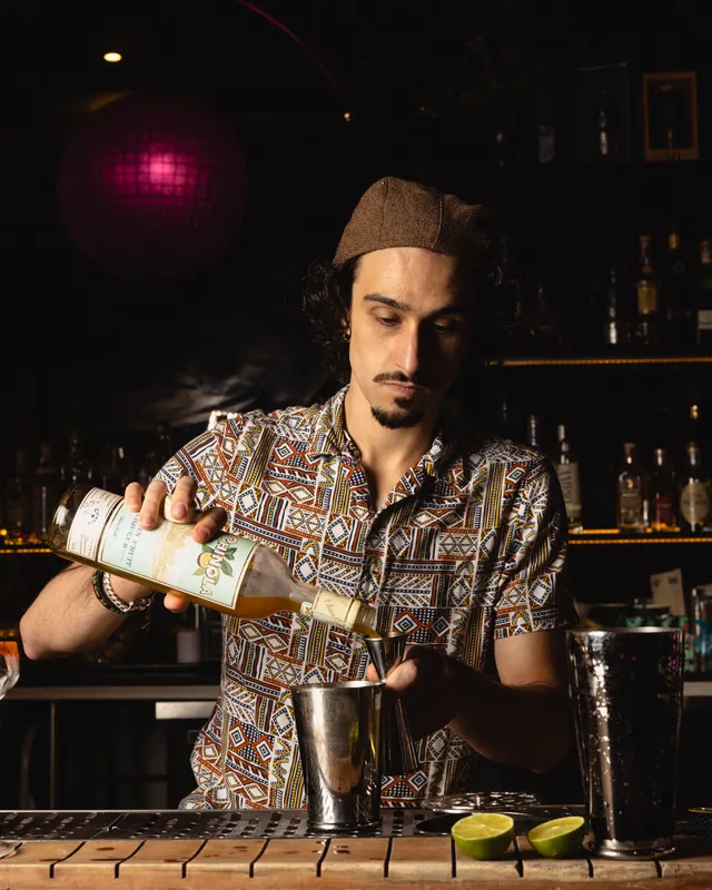 A bartender pouring a build at the backbar under a magenta light at Sobre Mesa, Oakland