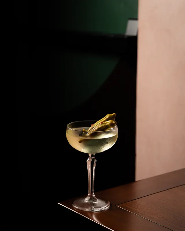 A coupe with a pickled pepper across the rim, lit from the side on the table edge in near darkness at Stereo 41, Walnut Creek