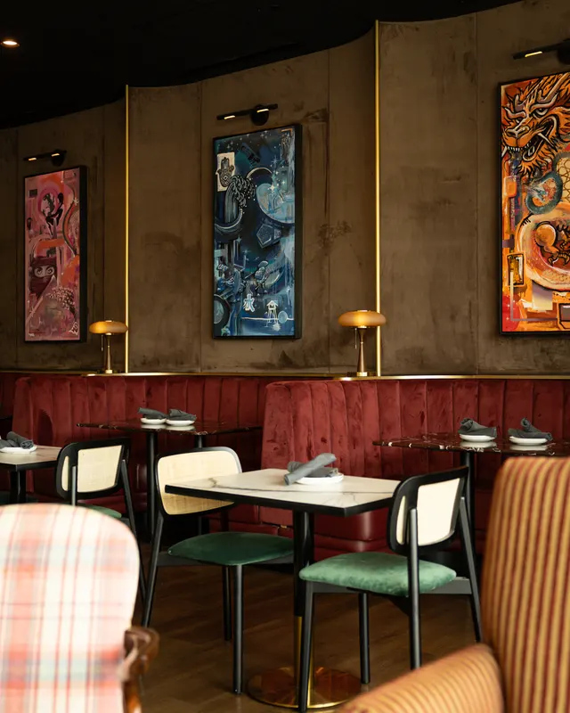 Red velvet banquettes, cane-back chairs and mushroom lamps under three paintings at Stereo 41, Walnut Creek