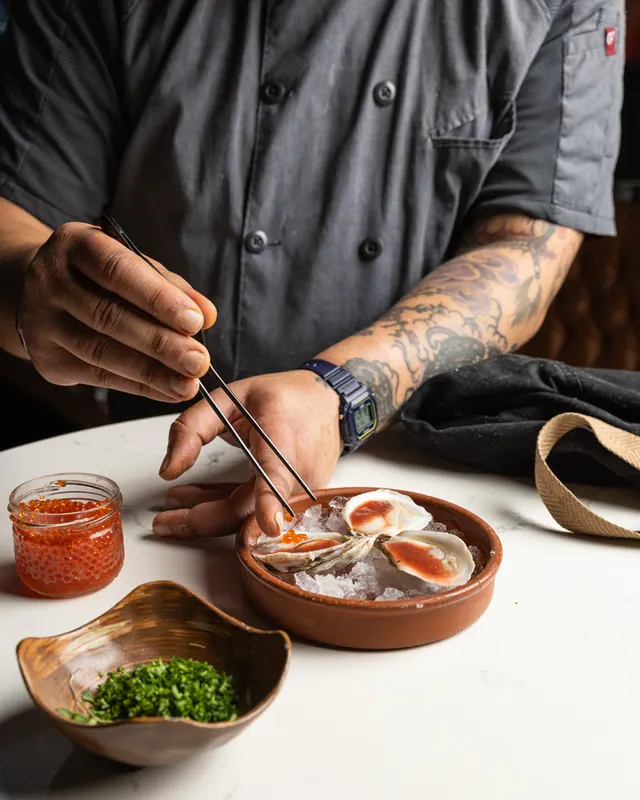 Tweezers placing the last element on a crudo - test-kitchen styling in progress, by Lemonad Media