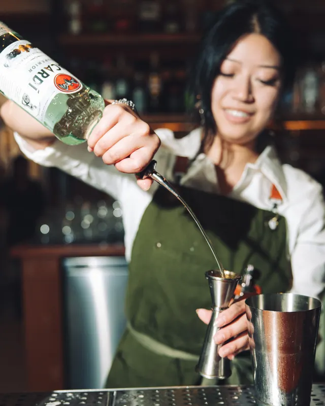 A bartender in a green apron pouring into the tin at Suspiro, Santana Row, San Jose