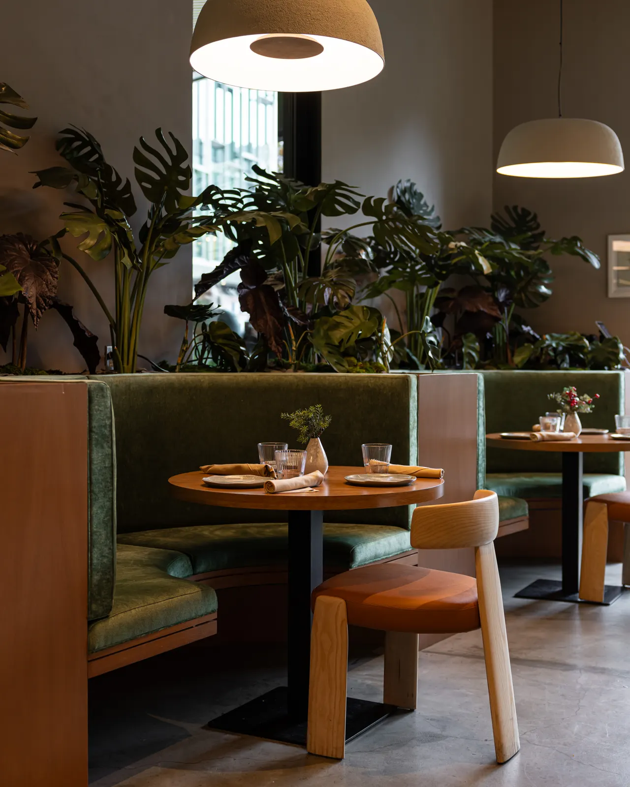 A green velvet booth under monstera and dome pendants at Suspiro, Santana Row, San Jose