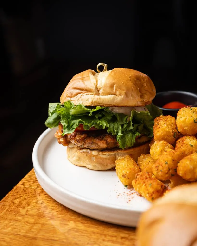 Plated salmon burger with seasoned tater tots at Town Tavern, Alameda