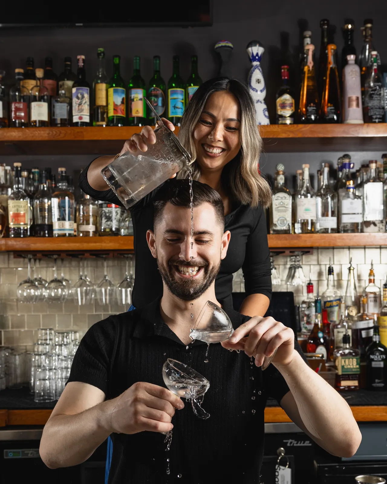 Two bartenders mid-pour behind the bar at Town Tavern, Alameda