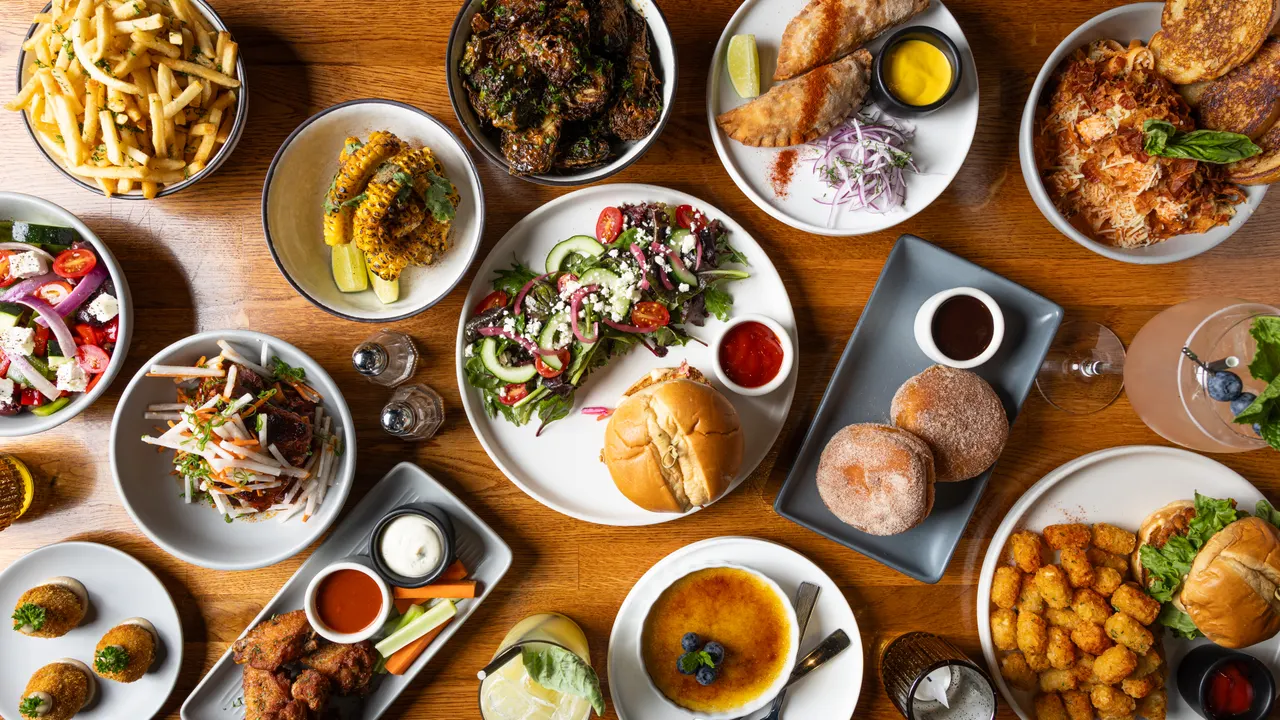 The full table from above at Town Tavern, Alameda: fries, charred corn, wings, empanadas, salads, burgers, and creme brulee