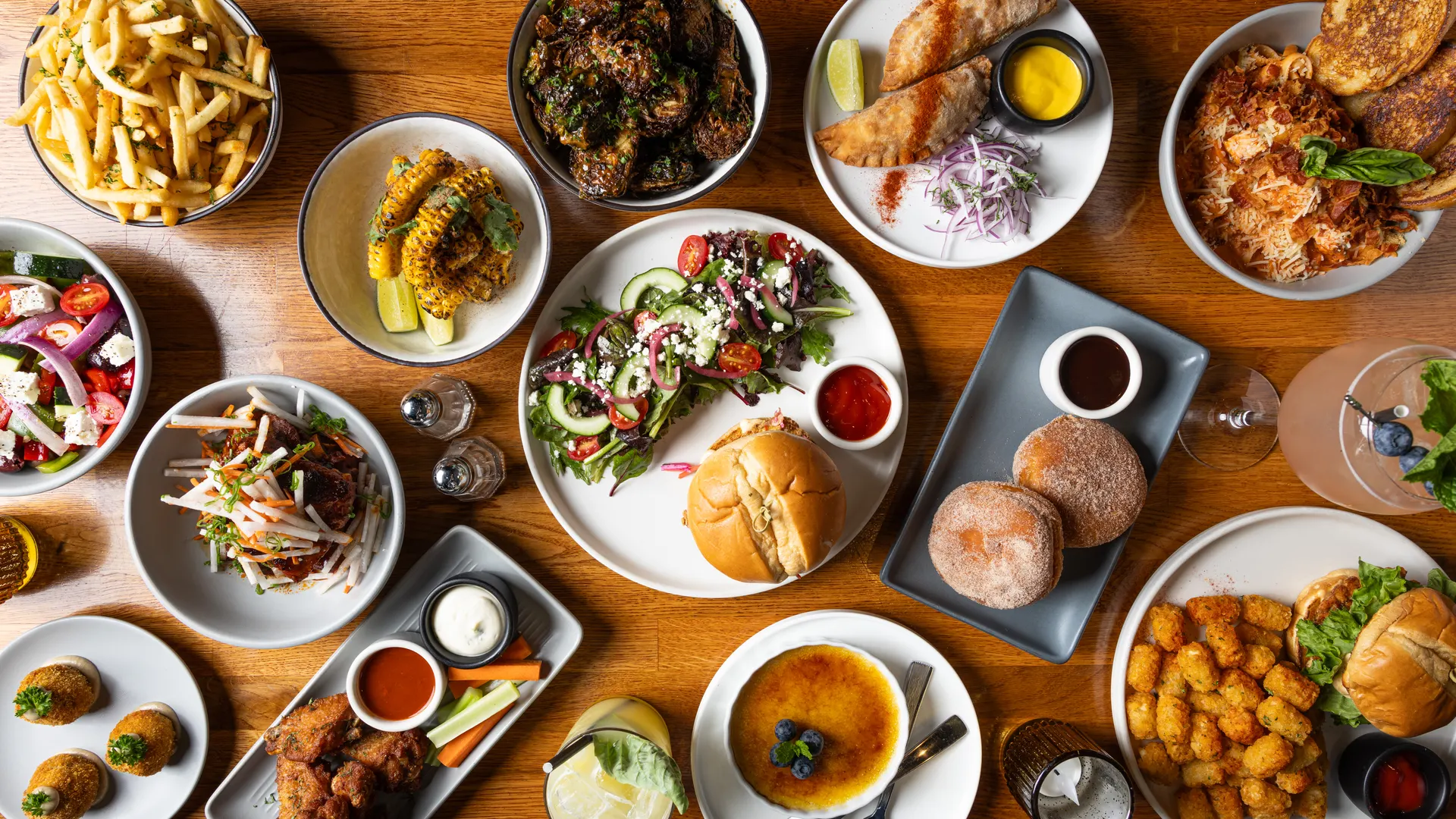 The full table from above at Town Tavern, Alameda: fries, charred corn, wings, empanadas, salads, burgers, and creme brulee