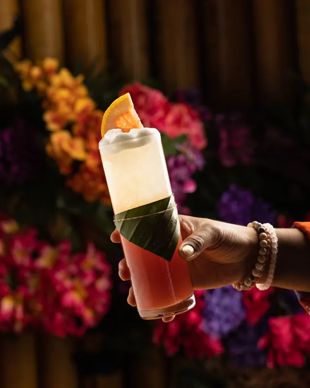 A banana-leaf-wrapped highball held against the flower wall at Trader Vic's, Emeryville