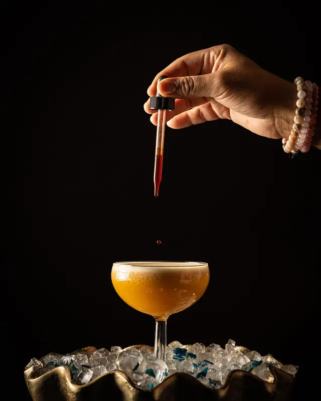 A dropper of bitters over the finished coupe at Trader Vic's, Emeryville